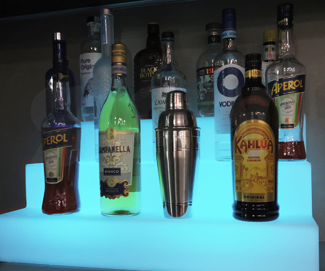 A bar with a stunning display of glowing liquor bottles on a shelf.