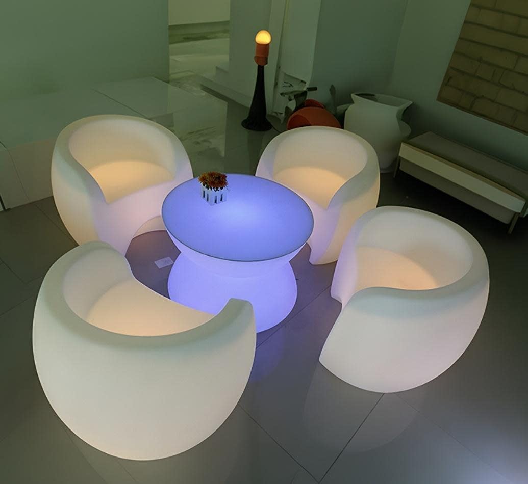 A set of white chairs and a table in a room available for Glow Couch Hire.