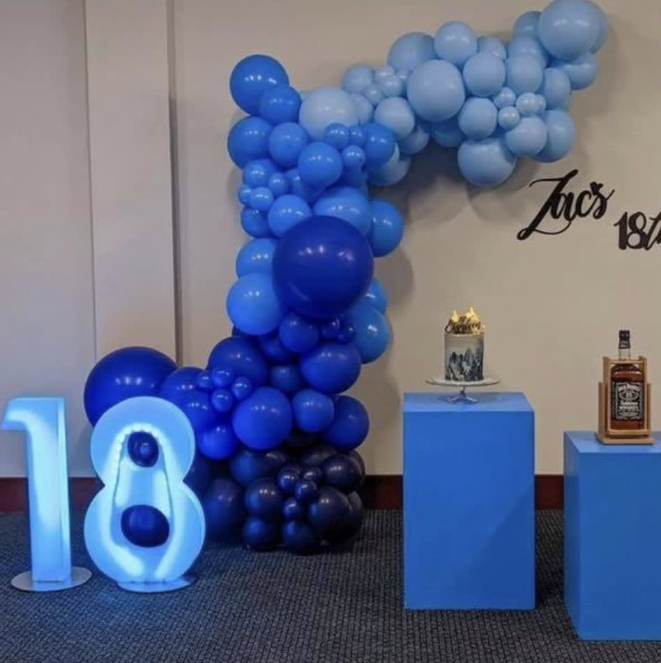 A blue balloon arch with a number 18 glowing on it.