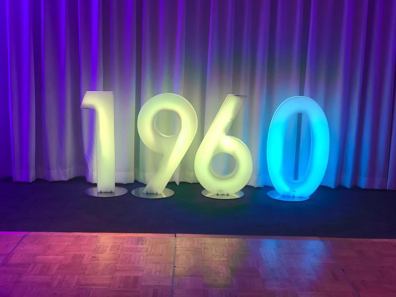 The number 70 is glowing on a stage in front of a curtain.