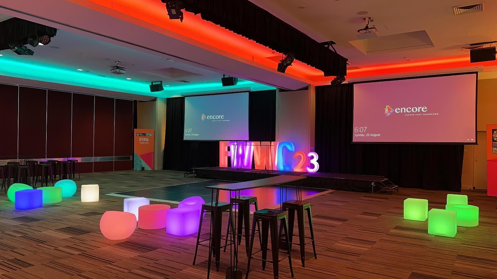 A conference room with colorful stools and a projection screen available for Glow Sphere Chair Hire.