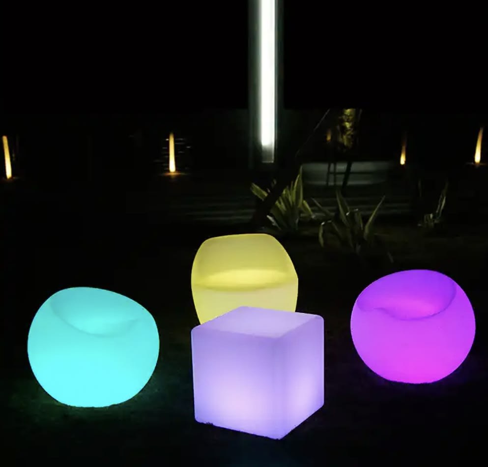 Three colorful glow sphere chairs on a grassy area.