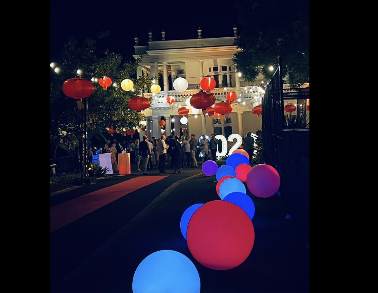 A group of people are walking down a street at night, carrying a mesmerizing 60cm Glow Sphere Hire.