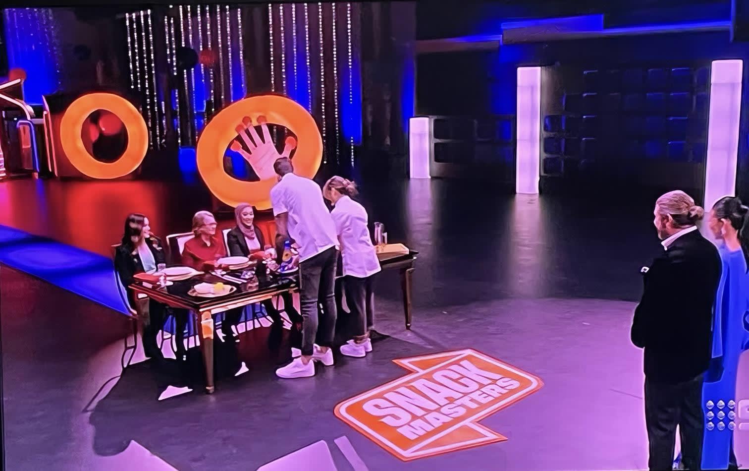 A group of people are standing in front of a television at a Glow Square event.