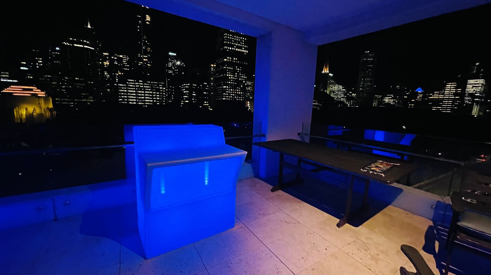 A glowing blue lit table with a stunning view of the city.