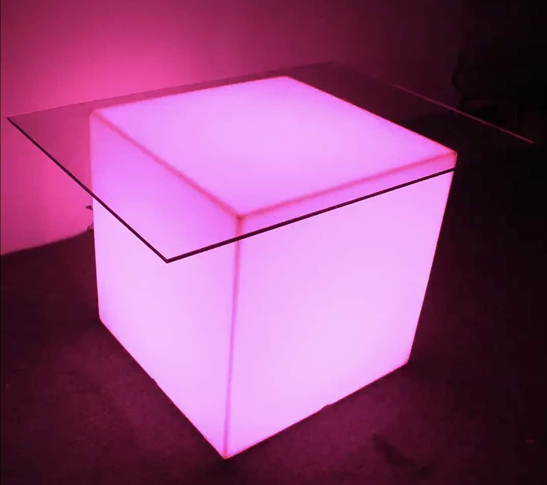 A large pink led cube table in a dark room.