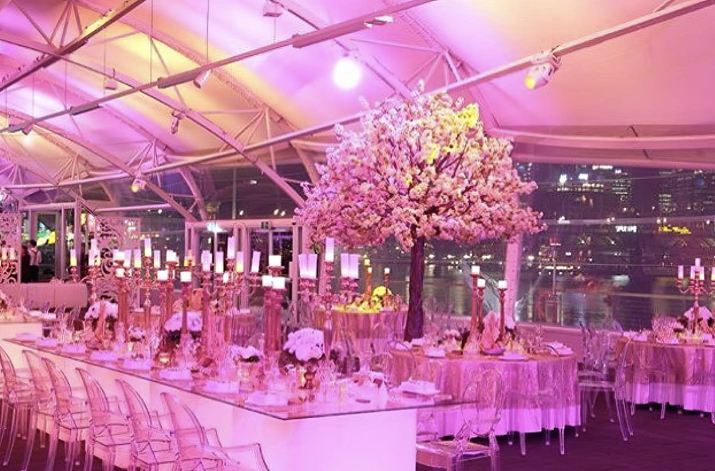 A wedding reception set up with pink lights and Square Glow banquet table hire.