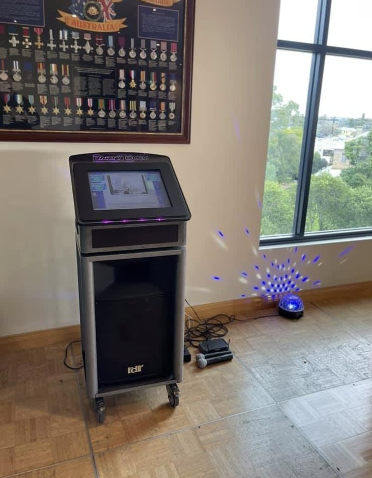 A computer with a Jukebox & Karaoke Hire package is sitting on a table in front of a window.