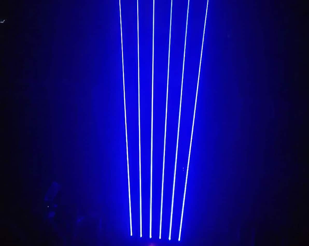 A blue light is shining on a stage in a dark room. Blue laser light illuminates the stage, creating a captivating atmosphere during events and performances.