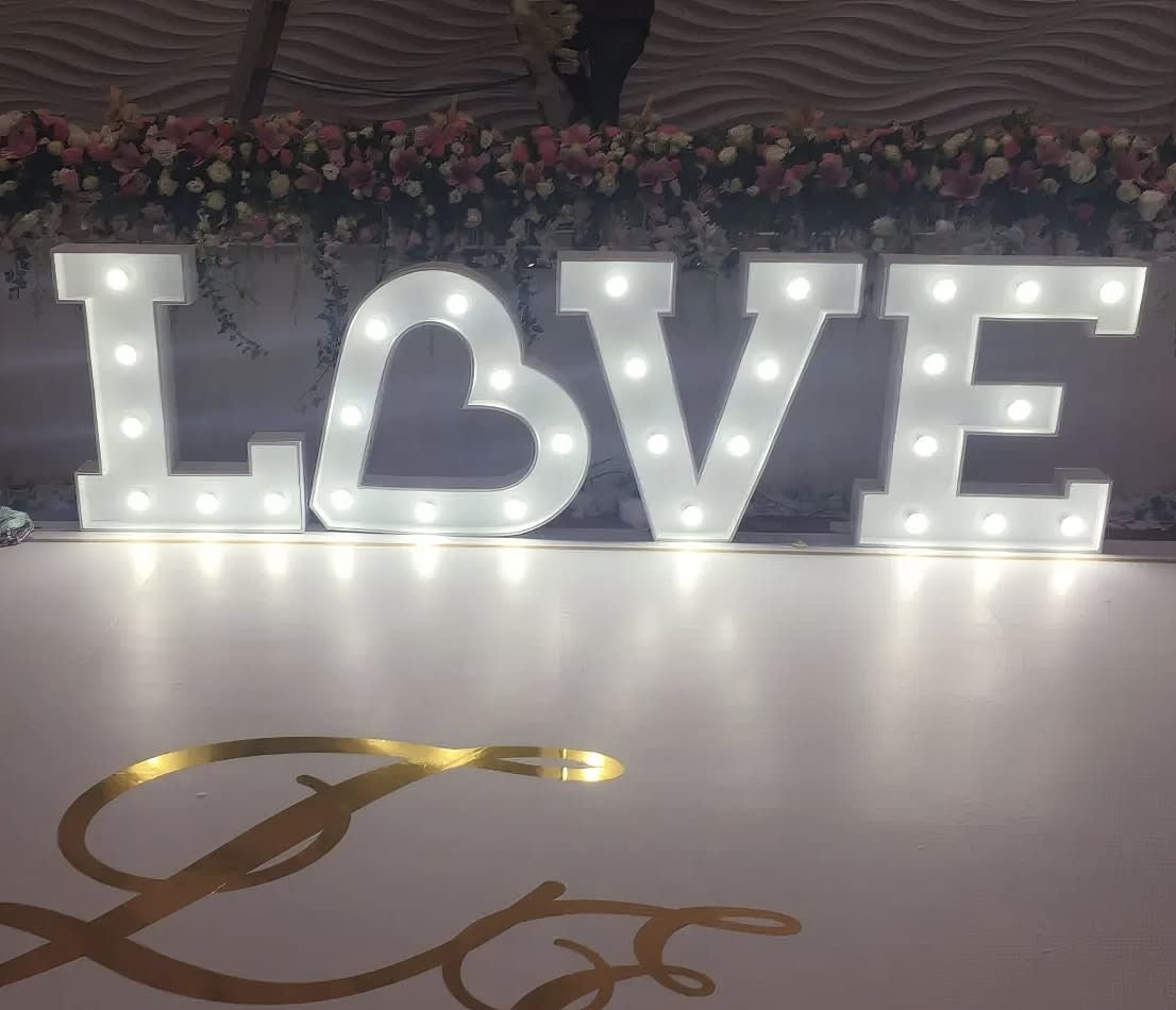 A large light up white letter 'love' on a white floor.