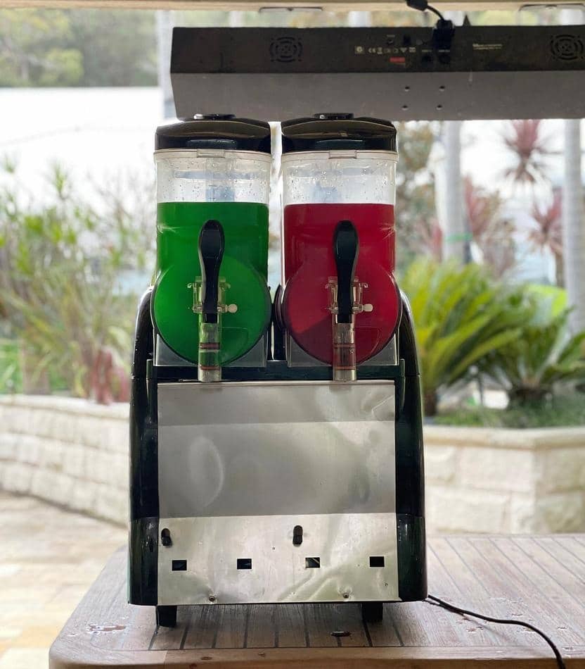 Two soda dispensers, one functioning as a slushie machine from Package 2, are sitting on top of a table.