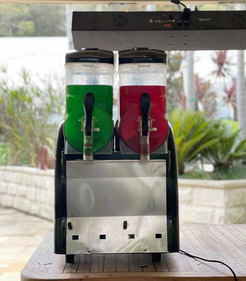 Two soda dispensers sitting on top of a table, available for Slushie Machine Hire.