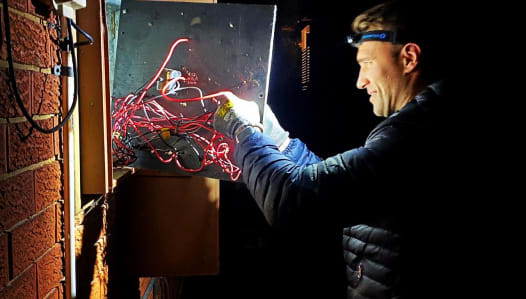 Drew performing an emergency electrical repair on a switchboard