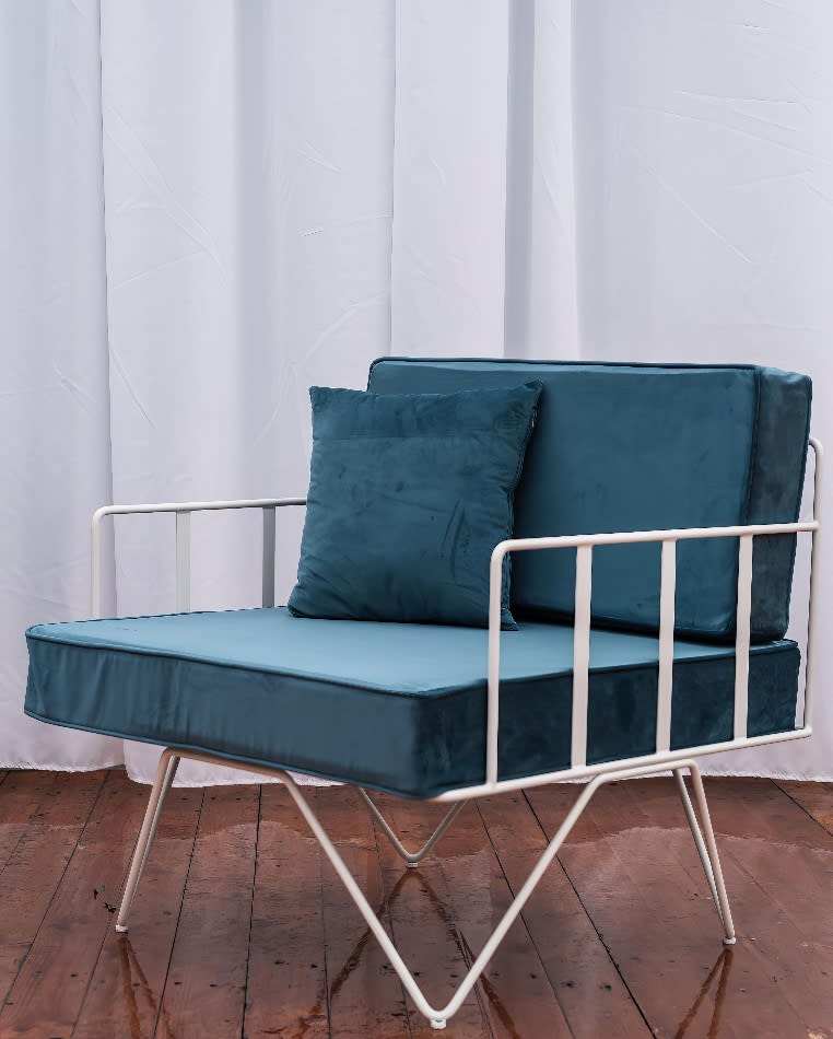 A wire lounge arm chair with green velvet cushions