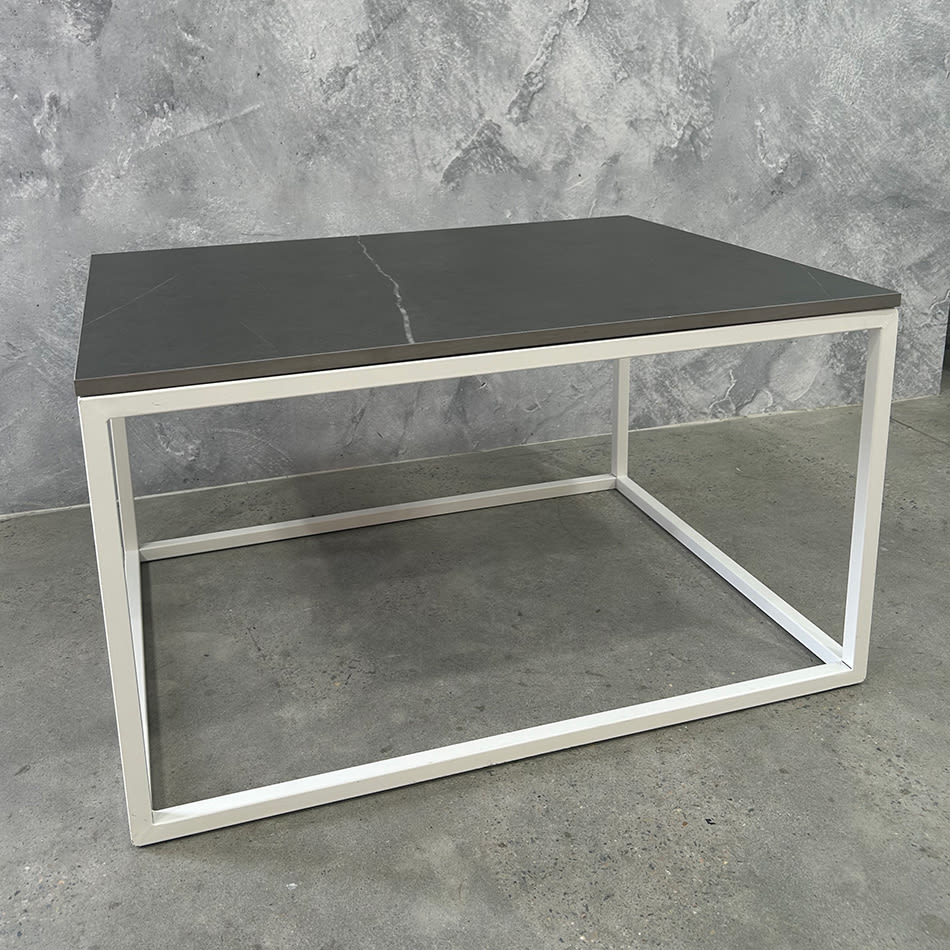 White Rectangular Coffee Table Hire w/ Black Top next to a marble wall