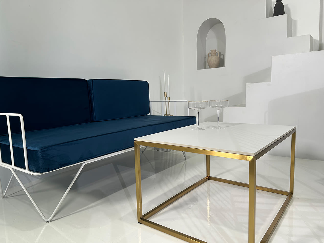 Gold rectangle a coffee table next to a blue velvet lounge