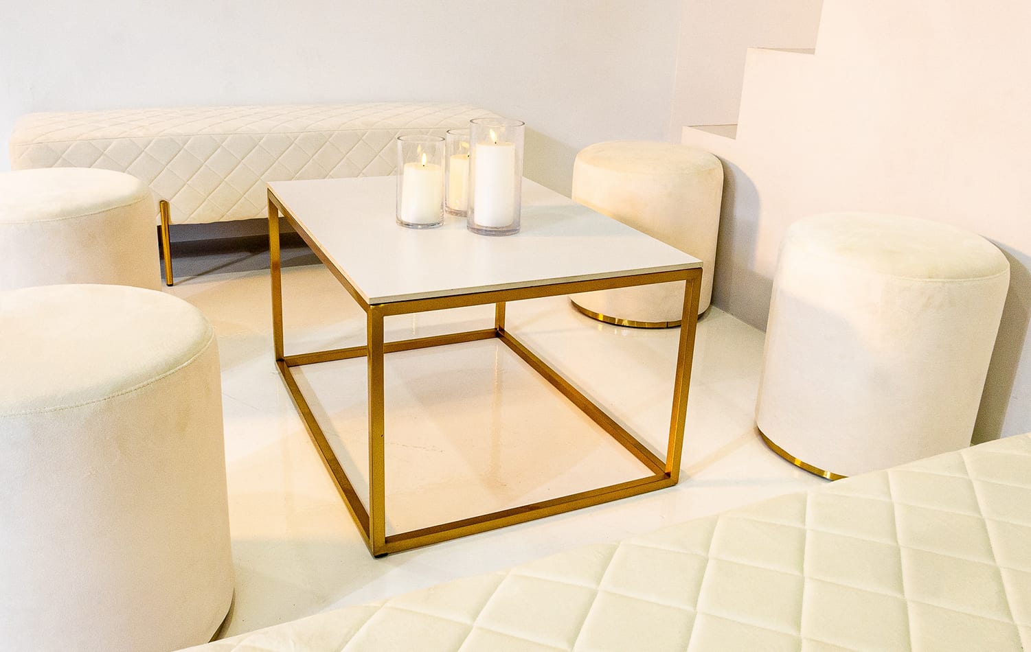 Four white ottoman stools next to a white coffee table