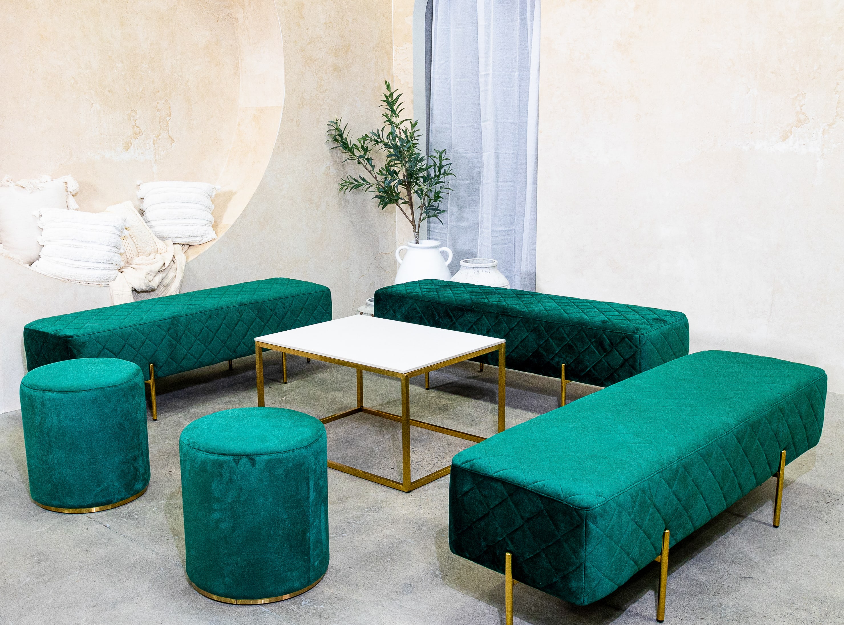 Green velvet ottoman stools next to an ottoman lounge