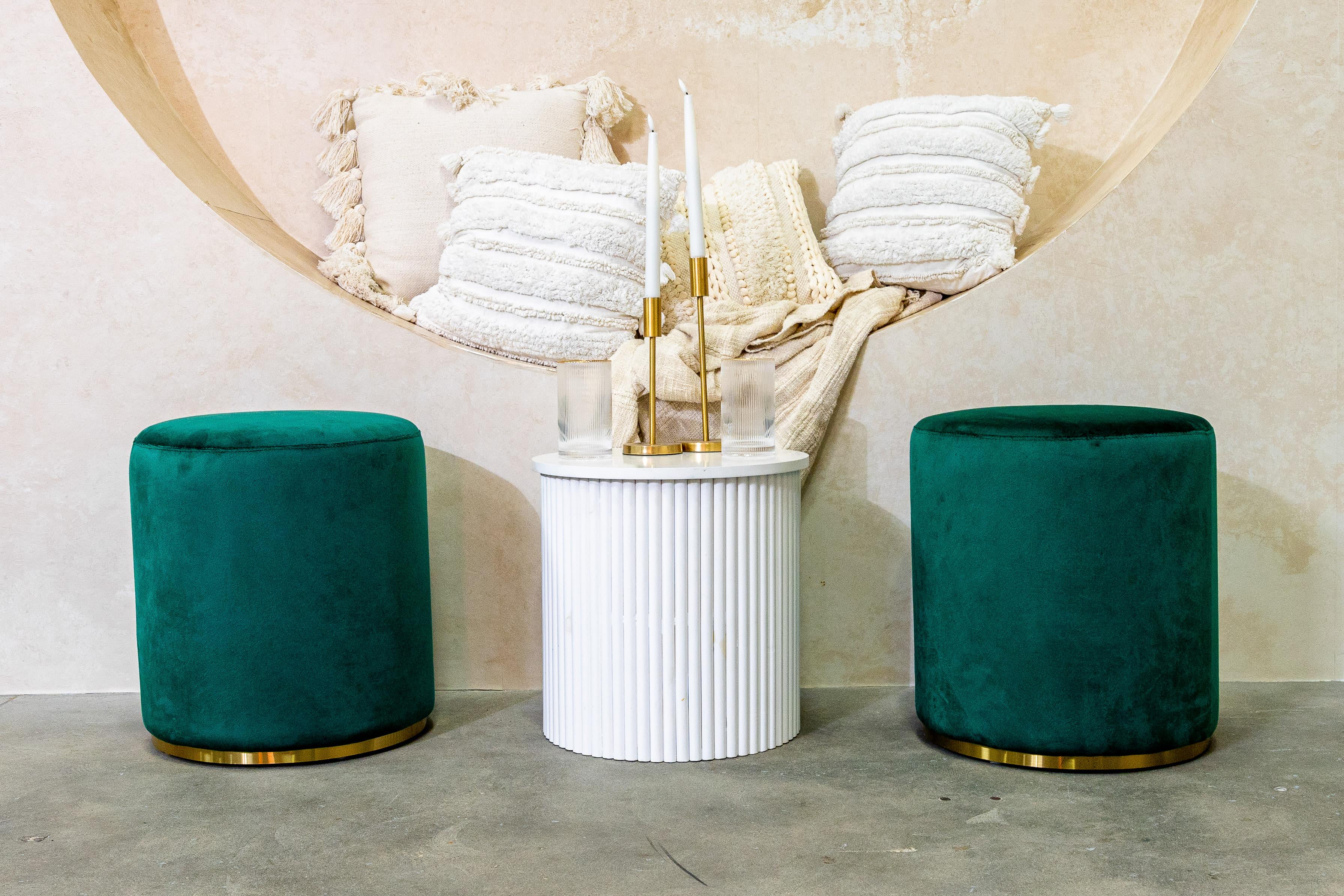 Two green velvet ottoman stools on display