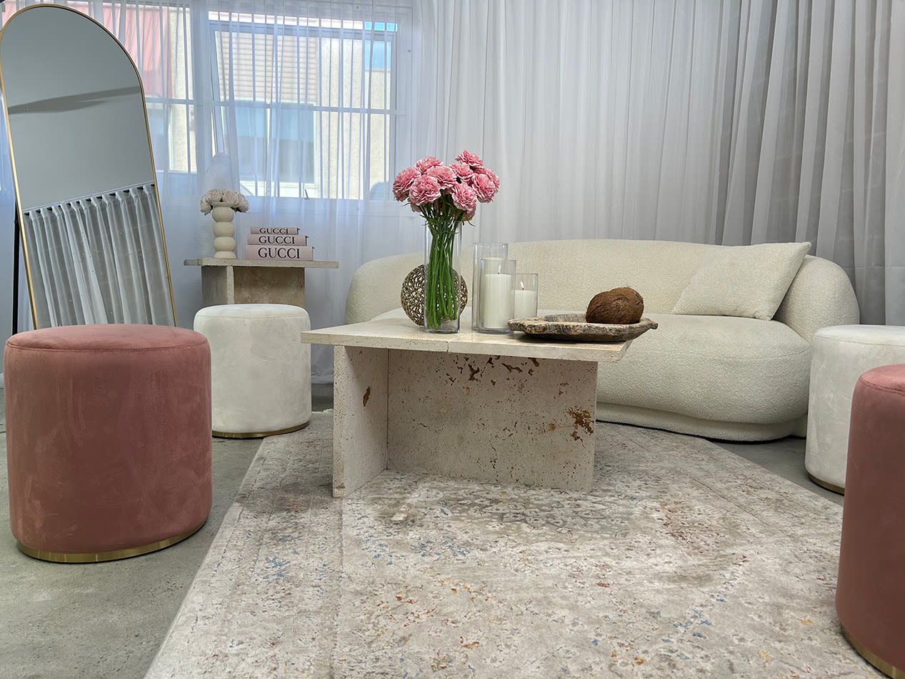 A white lounge setting with a pink velvet ottoman stool