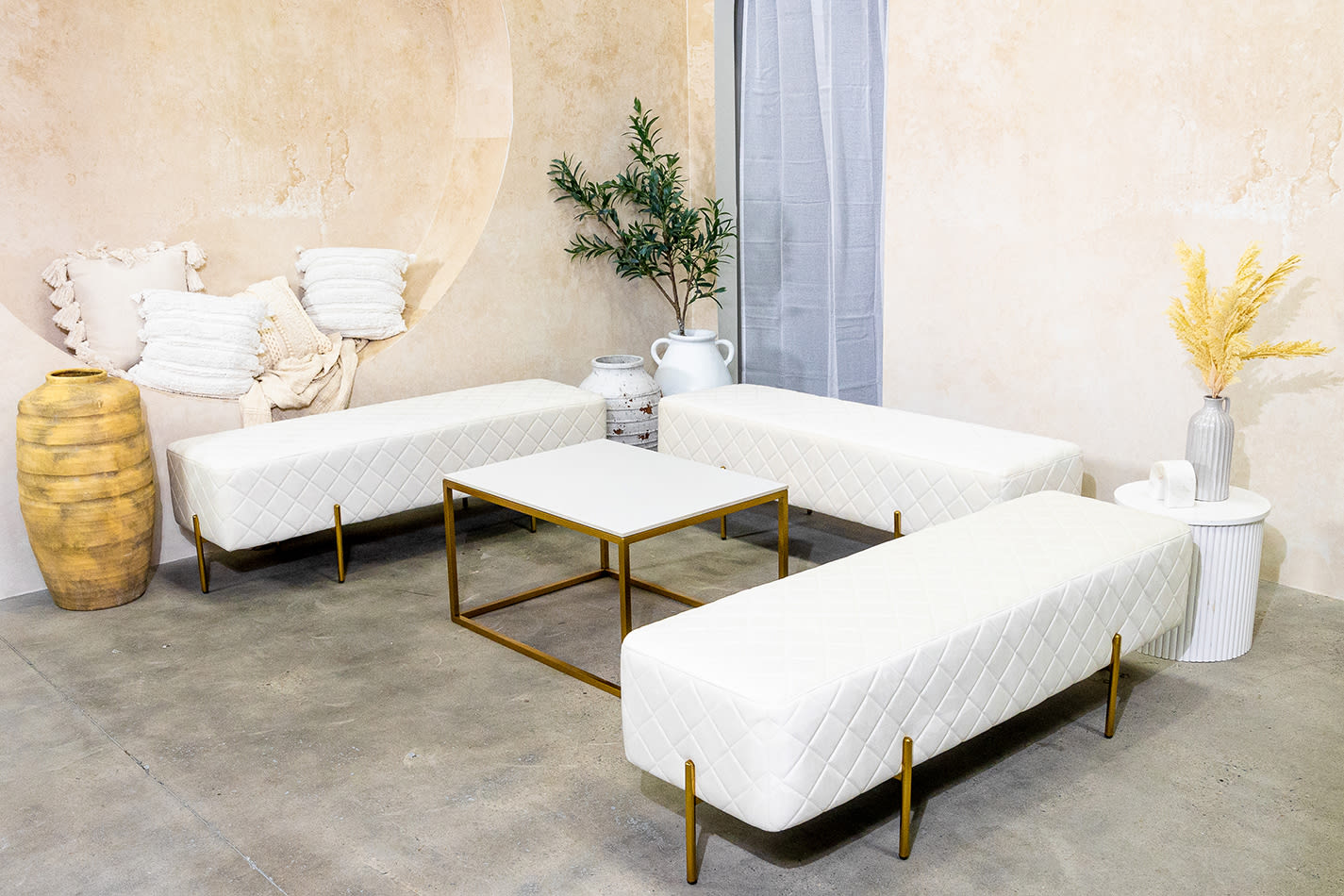 White velvet ottoman benches around a coffee table