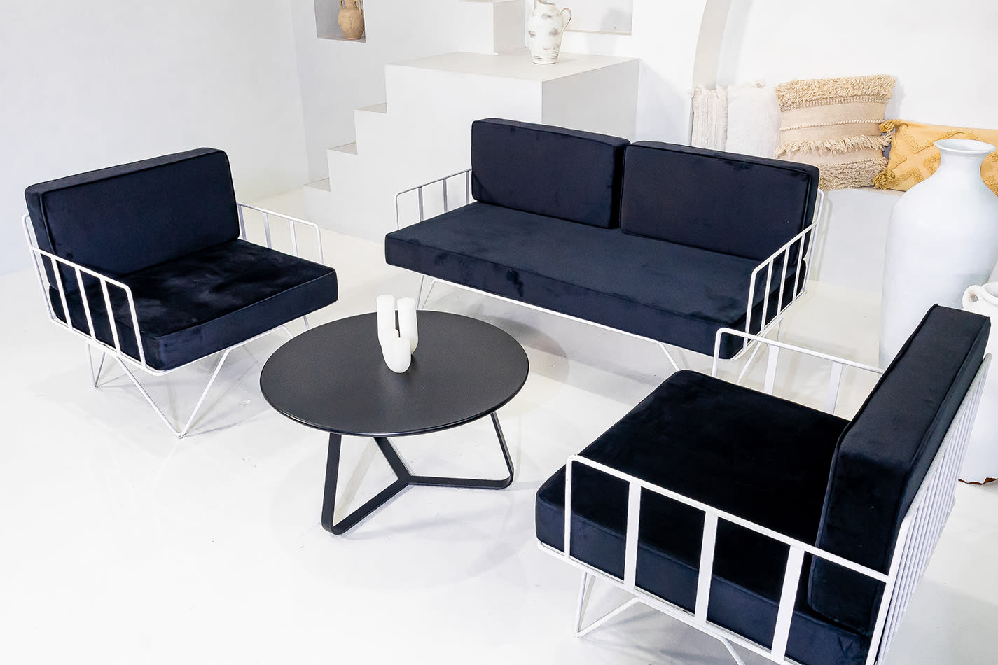 A white wire lounge set with black velvet cushions around a coffee table