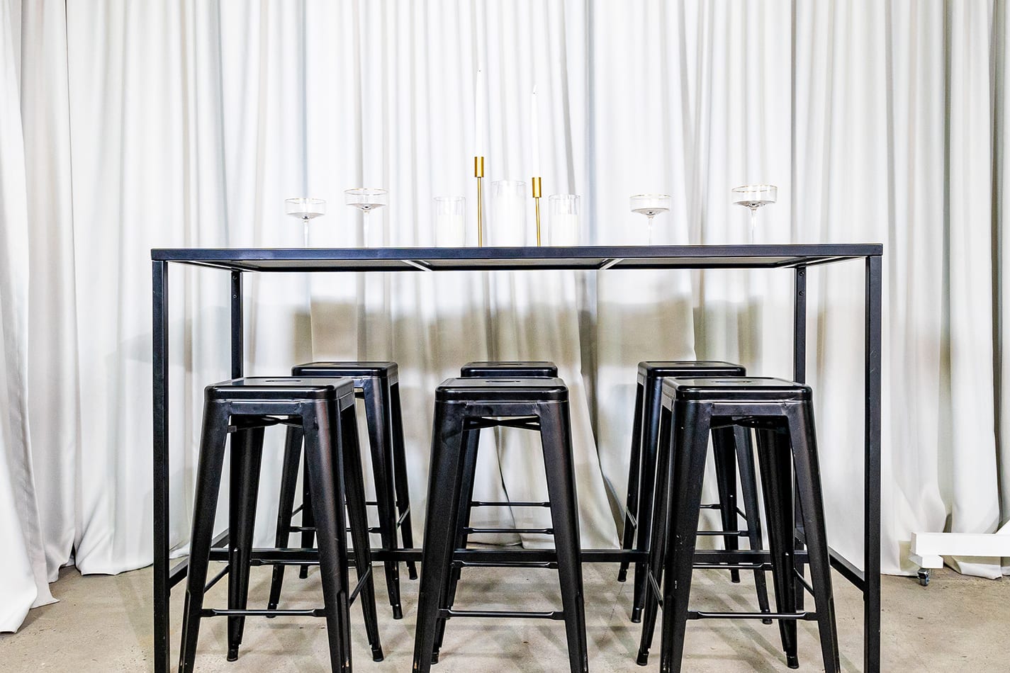 A black rectangular tapas table with stools underneath it