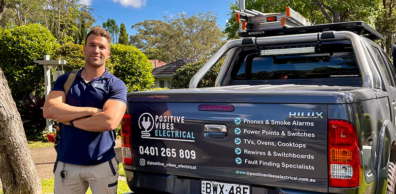 Drew from Positive Vibes Electrical standing next to his van