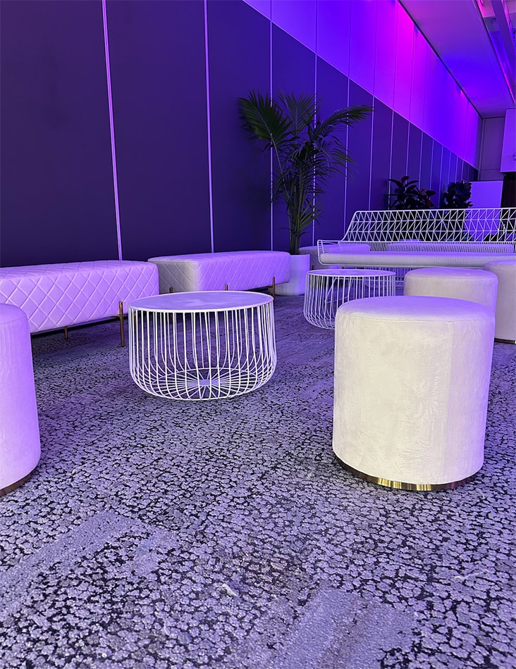 A white wire table next to a lounge setting in beautiful purple light