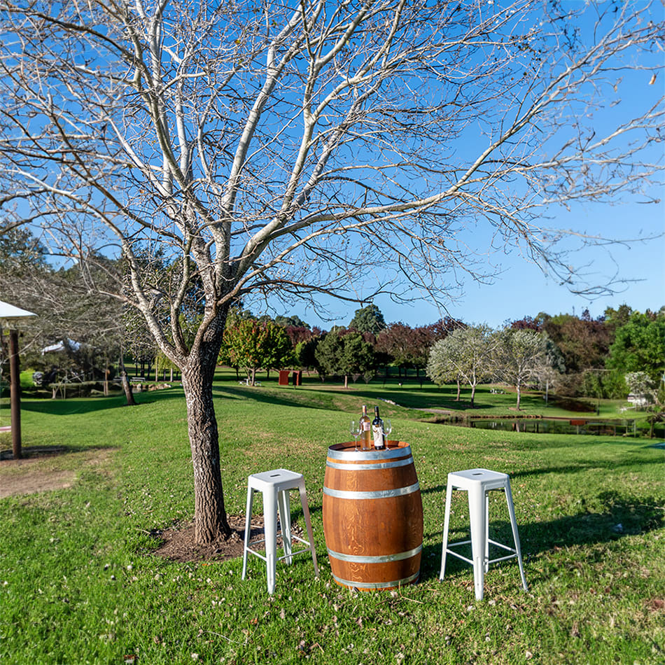 A beautiful outdoor setting with a wine barrel and some stools around it