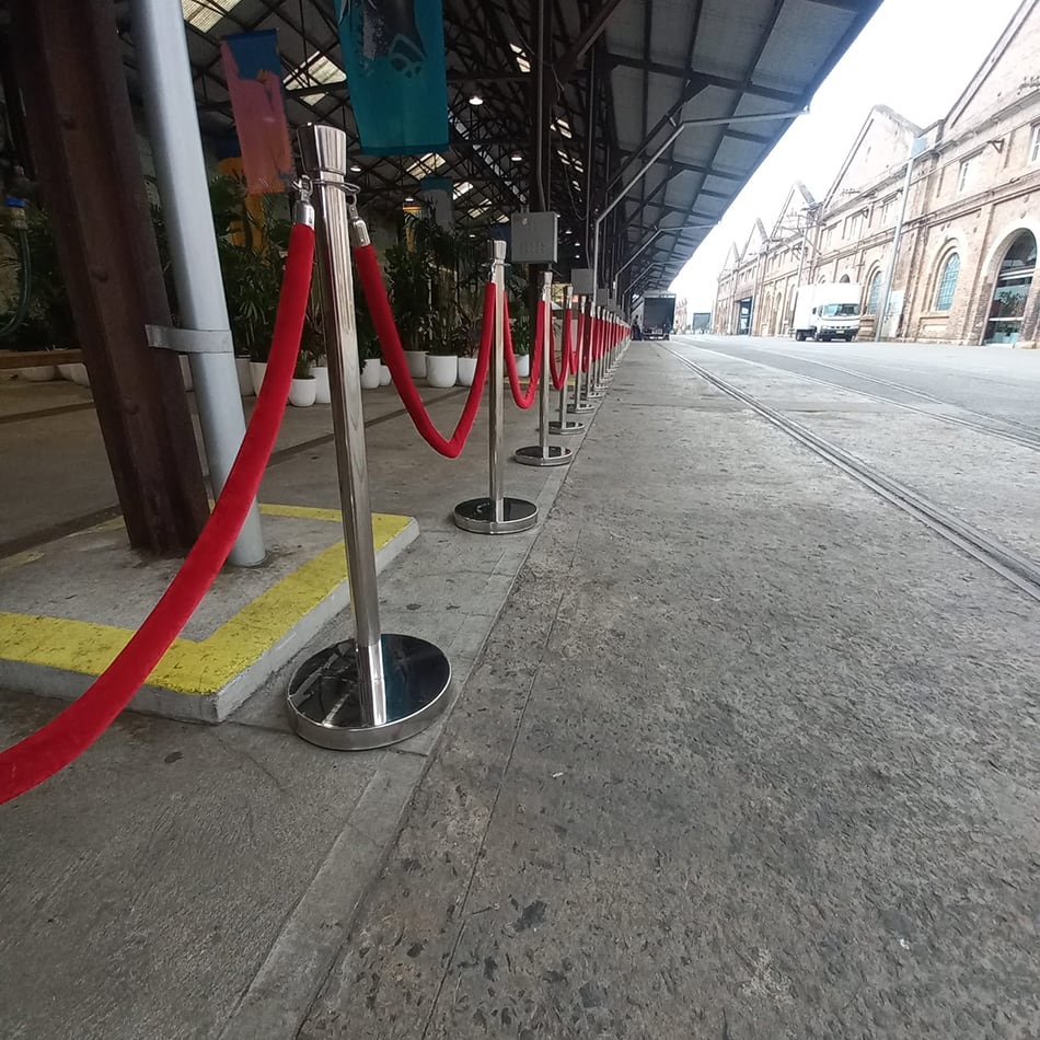 Close-up view of red velvet rope chrome bollard