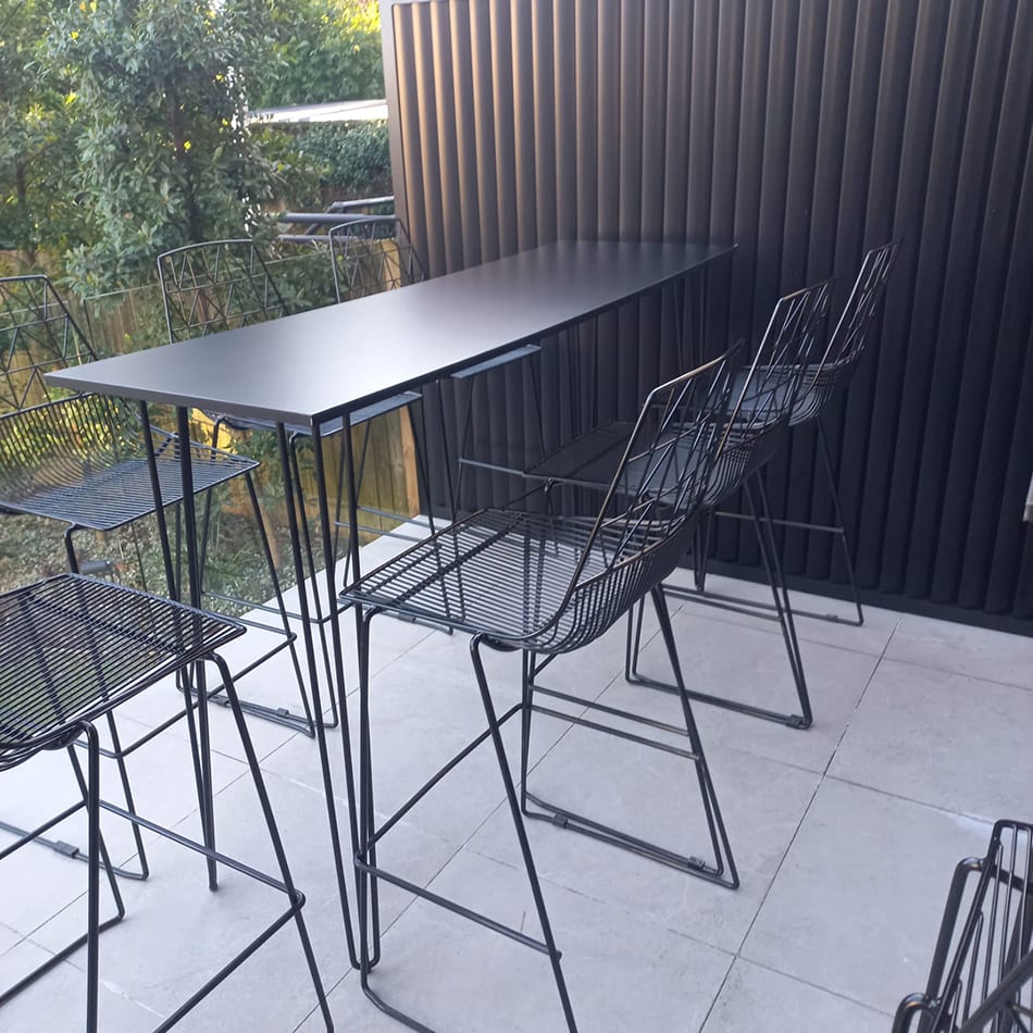 Black hairpin high bar table set up on a balcony with wire stools