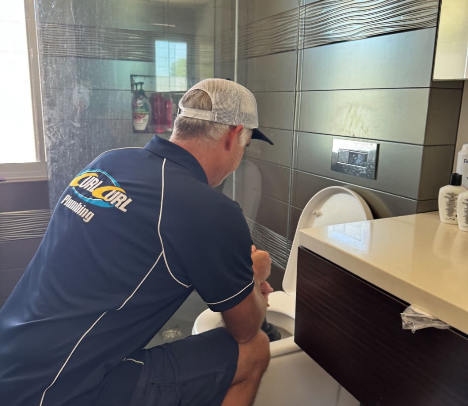 A plumber unblocking sewerage pipes for a toilet in Brookvale