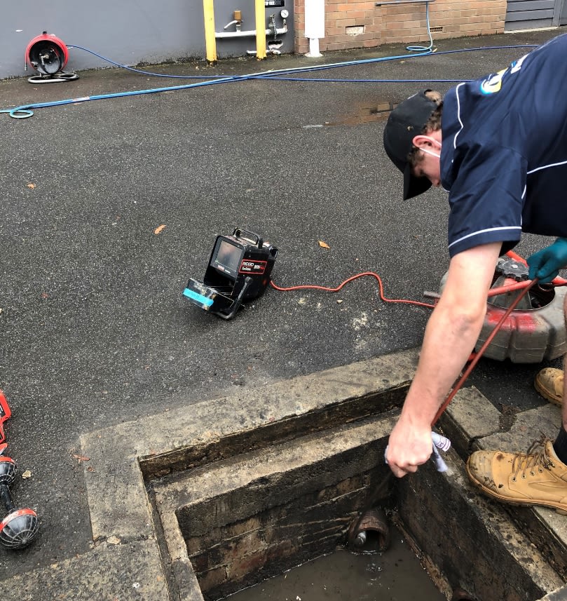 A plumber unblocking a stormwater drain in Brookvale