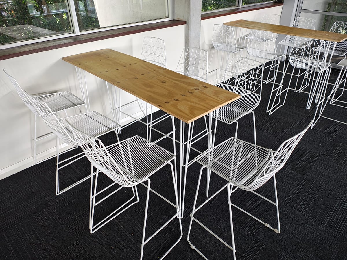 Timber top hairpin table surrounded by white wire stools