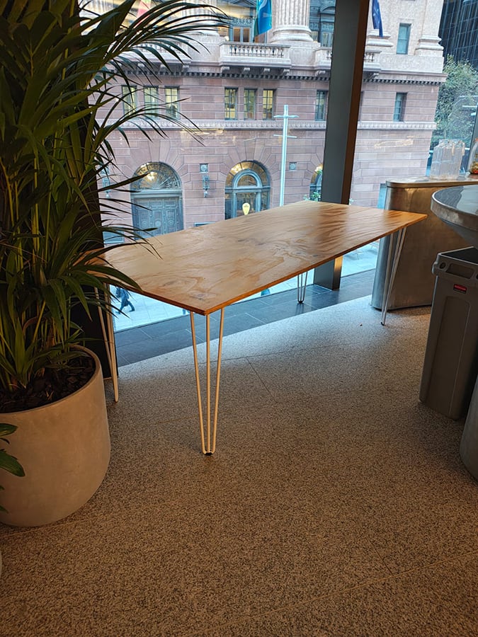 Our timber top hairpin table next to a window overlooking a building