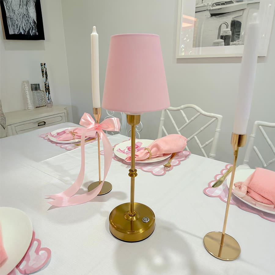 A pink shade table lamp on a table with decorations