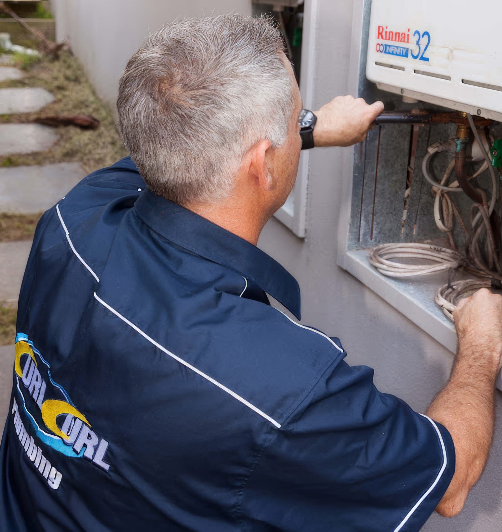 A plumber working on changing a gas hot water system to a heat pump hot water system