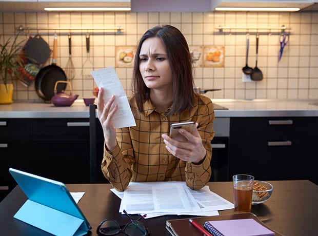 Woman looking at receipts with computer and smartphone