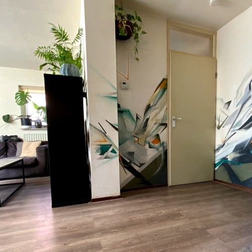 Abstracte muurschildering met graffiti-letters in een woonkamer – uitgevoerd met spuitbus en geïntegreerd in de ruimte.