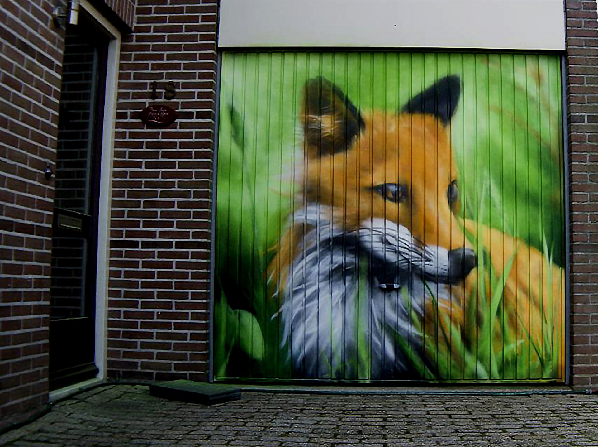 Schildering van een vos op metalen garagedeur – realistisch gespoten met spuitbus, met een knipoog naar de familienaam.