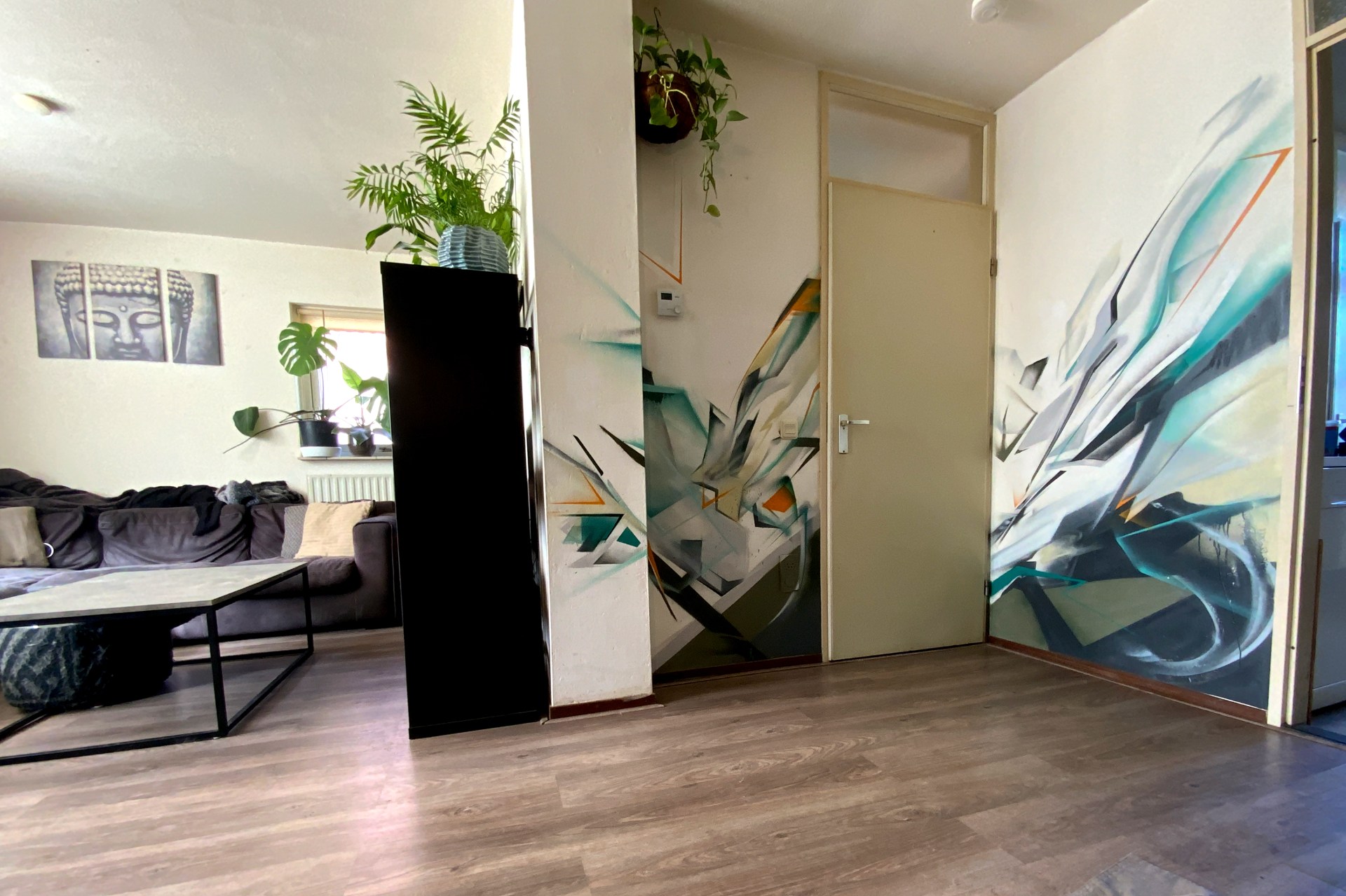 Abstracte muurschildering met graffiti-letters in een woonkamer – uitgevoerd met spuitbus en geïntegreerd in de ruimte.