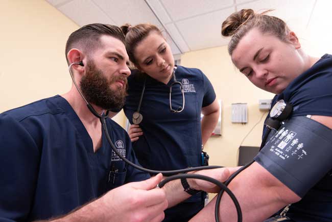 Two nursing students checking the blood pressure of another averett nursing student