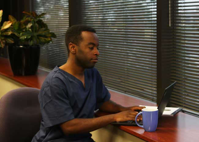 male nursing student studying on a computer from home