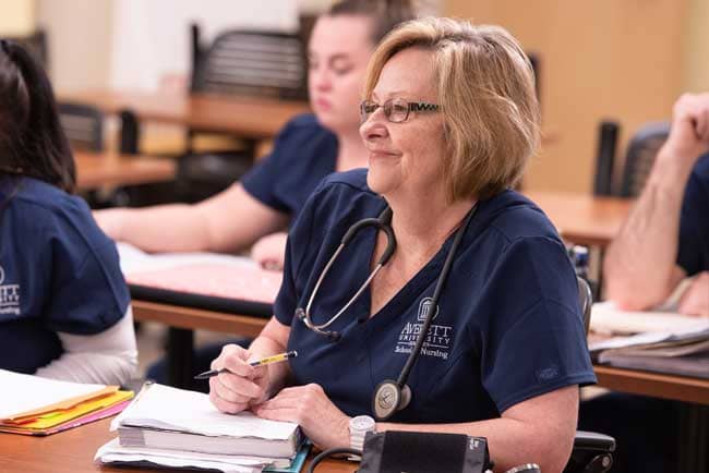 nursing student sitting at desk with textbooks