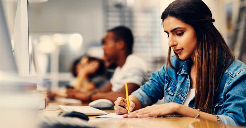 woman sitting at desk writing on paper