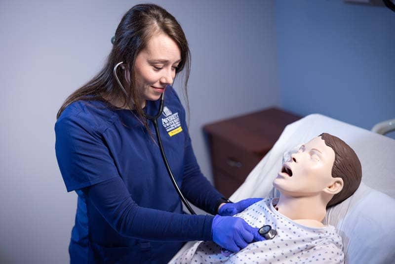 ABSN student using stethoscope on sim manikin