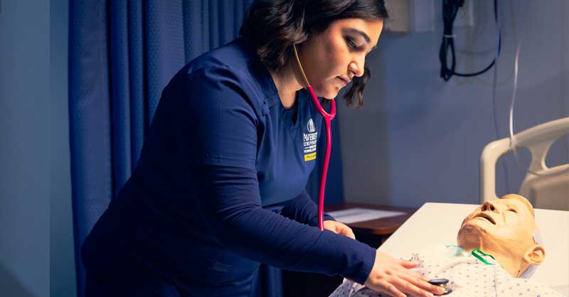 Averett nursing student practicing with a patient simulator during a skills lab