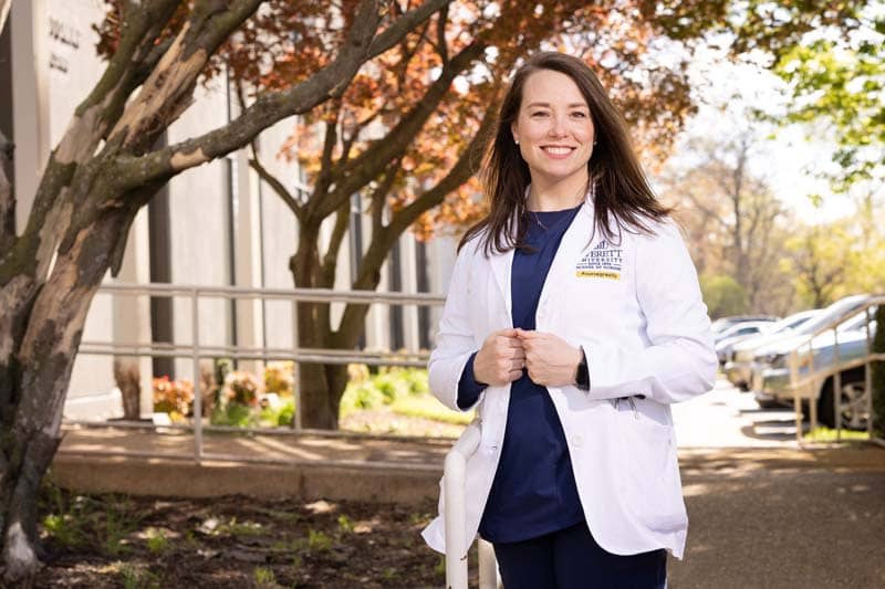 ABSN student standing outside by tree