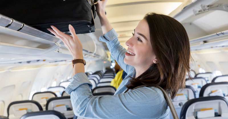 A travel nurse placing a suitcase in the plane.